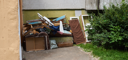 A Large Pile Of Rubbish Under The Windows Of A House
